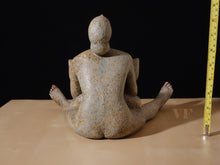 Load image into Gallery viewer, View of seated female figure&#39;s back of a ceramic sculpture on a beige table surface with a black background, accompanied by a measuring tape.
