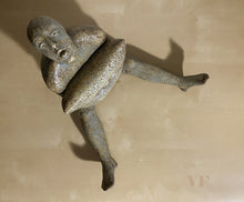 Load image into Gallery viewer, Birds eye view of ceramic sculpture of a figure squeezing a pillow to her torso with legs extended on a light wood table background
