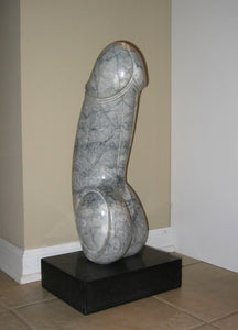 A human phallus / dick / penis is carved out of a piece of grey marble with slightly darker veins in the stone.  Black rectangular base keeps this vertical sculpture from tipping.  Marble art by Vasily Fedorouk