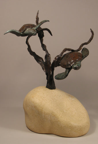 Sea Turtles seem to fly near a kelp plant. sculpture in bronze with limestone curvy hand-carved base that implies the sandy sea floor