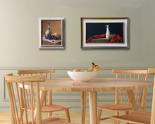 Load image into Gallery viewer, dining room in sea foam green and natural wood table and chairs help put the focus on these two paintings of Italian food specialties, wine, cheese, olives and olive oil.  Both framed paintings are by artist Kelly Borsheim

