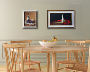 dining room in sea foam green and natural wood table and chairs help put the focus on these two paintings of Italian food specialties, wine, cheese, olives and olive oil.  Both framed paintings are by artist Kelly Borsheim