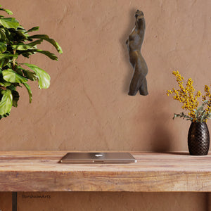 the bronze wall-mounted statue of a female dancer torso looks great on this warm light brown wall of a home office.