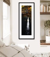 Load image into Gallery viewer, Offset mat and thin black frame really enhance this pastel drawing print of the buildings on the Ponte Vecchio old bridge in Italy at night with a turquoise boat floating parked on the Arno River... shown here in a boho bedroom scene, art for travel lovers
