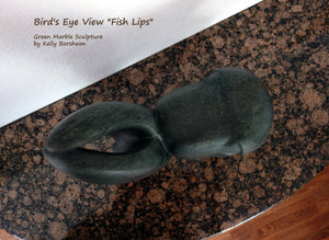 Bird's eye view of the stone carving Fish Lips by Kelly Borsheim, resting on a granite tabletop.