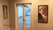 Load image into Gallery viewer, Shown here in a home that has a room overlooking an outdoor patio, gracing the wall with an original painting by the same artist.  The Triumph of Icarus is hung where he gets the most visibility in this living room.  Your choice of frame on the print.  Art by Kelly Borsheim
