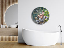 Load image into Gallery viewer, Lollipop, a round painting celebrating the innocence of youth, a young boy sits on a rock looking into a river.   His nude figure is surrounded by tree leaves, increasing his alone time in nature.  Shown here with an elegant bathroom featuring a round window.

