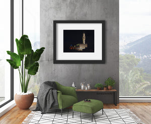 Palazzo Vecchio at Night, a pastel drawing on black paper inspired by the City Hall architecture in Florence, Italy, shown here in mockup gray frame with wide white mat.  Loft apartment living room art by Kelly Borsheim