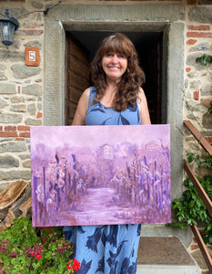 The artist Kelly Borsheim holds her painting Vineyard in Fog Montecarlo Tuscany for photographer Jane Sulicich, outside of her Tuscan home.