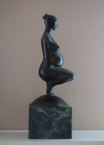 Profile view of Pregnancy, a female pregnant mamma squatting with legs together in a graceful, elegant pose, bronze figure statue, mounted on a green marble base, tabletop sculpture by Vasily Fedorouk, Ukrainian - American sculptor artist