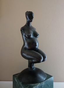 woman without arms and with hair in a bun, Pregnancy, a female pregnant mamma squatting with legs together in a graceful, elegant pose, bronze figure statue, mounted on a green marble base, tabletop sculpture by Vasily Fedorouk, Ukrainian - American sculptor artist