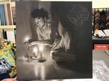Load image into Gallery viewer, The male portion of the triptych oil painting Luminosity.. a shirtless man sits half reclining, resting on one arm.  the other reaches out to touch the fire of the candlelight.  Celtic symbology of peace and connectedness is shown painted in silver in the upper right corner of the artwork
