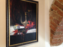 Charger l&#39;image dans la galerie, The framed painting, Turkish Light, a still life inspired by the Mediterranean and Turkey, with red and orange scarf and a white marble slab, shown here at art exhibit in Italy, next to a brick arch in the wall.
