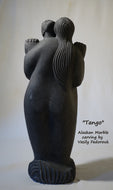 Tango a 2-foot tall stone carving in Alaskan marble of a closely dancing couple.  As he embraces her, she nibbles on his ear.  The figures are modern, abstracted or better, designed with minalist features and intertwined fingers.  A romantic sculpture, carved by Ukrainian-American artist and sculptor Vasily Fedorouk.  Vertical, standing figures.