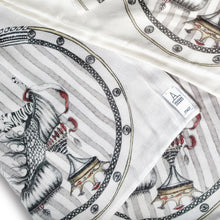 Load image into Gallery viewer, detail image of designer scarf Tiger Shoe foulard material, shown here the artist Dragana Adamov&#39;s logo tag sewn into one corner of the elegant scarf featuring hand-drawn tigers leaping from around a circus-inspired fantasy shoe
