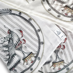 detail image of designer scarf Tiger Shoe foulard material, shown here the artist Dragana Adamov's logo tag sewn into one corner of the elegant scarf featuring hand-drawn tigers leaping from around a circus-inspired fantasy shoe