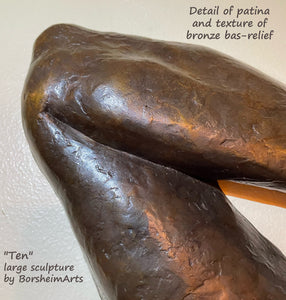 detail of bronze bas-relief figure sculpture to see the bronzy color of the patina, as well as the subtle textures in the nude figure wall sculpture of the back of a woman with Bob Fosse hands.  This is a detail image of her left elbow.  Title is "Ten" for her beauty and the number of digits on both hands. Artwork by artist Kelly Borsheim, limited edition bronze