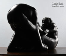 Laden Sie das Bild in den Galerie-Viewer, Her face looking at the man Helping Hands by Kelly Borsheim Couple Art Carved from a black marble called Bardiglio from Italy, this sculpture depicts a man bending over forward to help a seated woman stand up.  Her hands reach up towards his bearded face, but it is the moment before she is close enough to reach him. 
