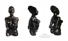 Charger l&#39;image dans la galerie, terra-cotta sculpture of a black woman with her hair pulled back into a large bun.  She stands tall and proud, her posture is slightly arched back with her arms folded together behind her, a beautiful physique
