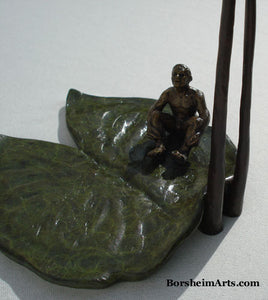 Looking down on the little bronze man sitting on a lily pad as he looks skyward.  bronze sculpture by Kelly Borsheim