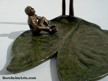 Load image into Gallery viewer, patina close up of green lily pad and little bronze figure man.  Sculpture by Kelly Borsheim Borsheim Arts Studio.
